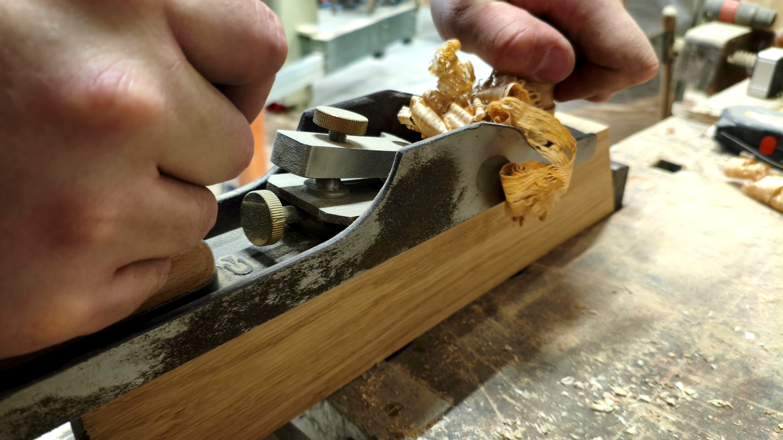 Roka mizarja pri glajenju hrastovega lesa z ročnim obličem
